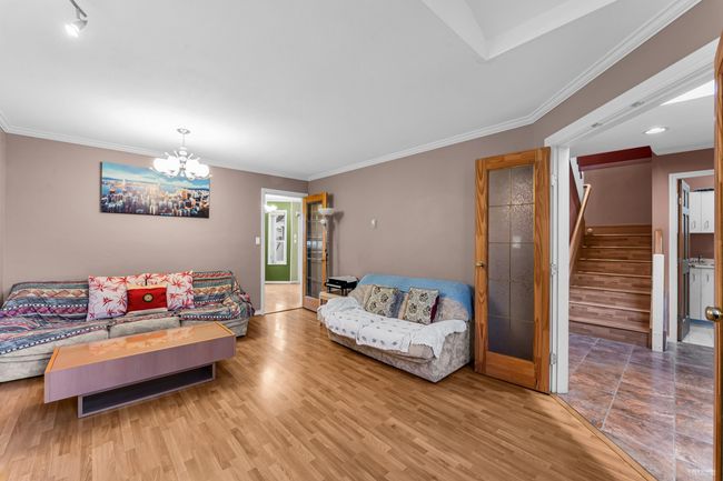 Living area featuring stairway, an inviting chandelier, crown molding, and wood finished floors | Image 4