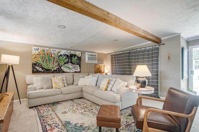 Carpeted living room with ornamental molding, an AC wall unit, a textured ceiling, and beam ceiling | Image 22