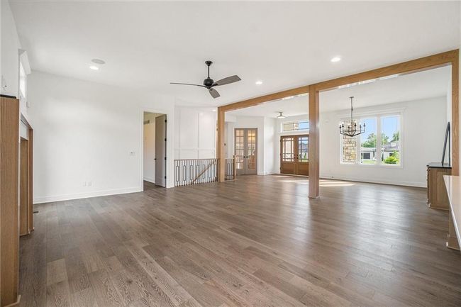 Unfurnished living room featuring wood finished floors, a chandelier, french doors, ceiling fan, and recessed lighting | Image 14