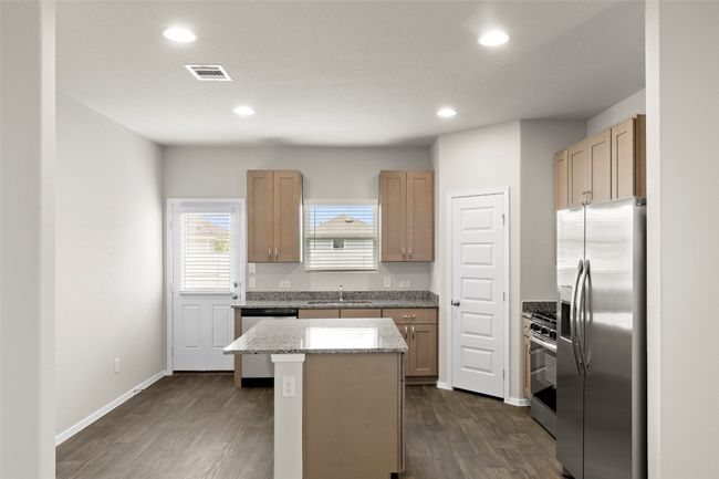 Kitchen featuring light stone countertops, a center island, dark wood-style flooring, a sink, and appliances with stainless steel finishes | Image 14
