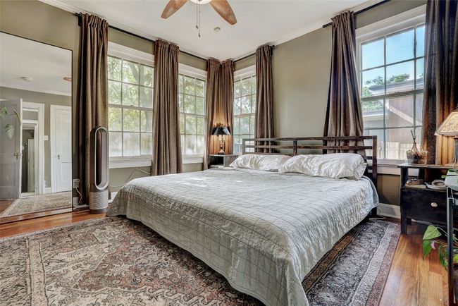 Bedroom with wood finished floors, ornamental molding, and multiple windows | Image 15