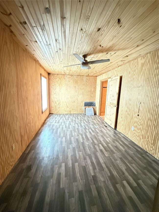 Unfurnished living room featuring wooden ceiling, wood finished floors, ceiling fan, and wood walls | Image 38