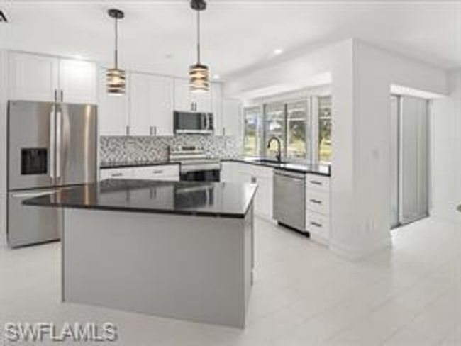 Kitchen with appliances with stainless steel finishes, white cabinetry, light tile flooring, and a center island | Image 4