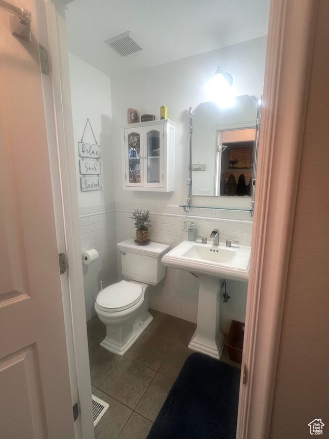 Half bathroom featuring tile walls, toilet, tile patterned floors, a wainscoted wall, and visible vents | Image 27