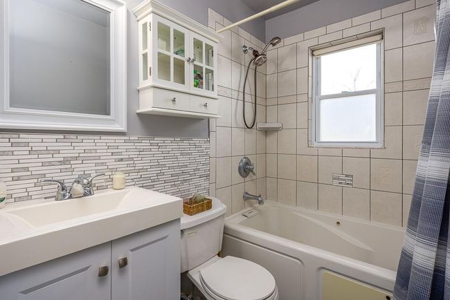 Full updated upstairs bath featuring vanity, shower / bath combo with shower curtain, tile walls and backsplash | Image 16