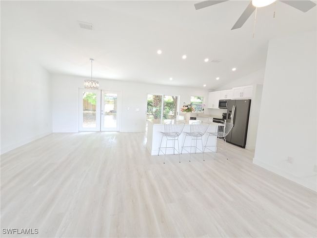 Unfurnished living room with recessed lighting, light wood-type flooring, a ceiling fan, lofted ceiling, and baseboards | Image 8
