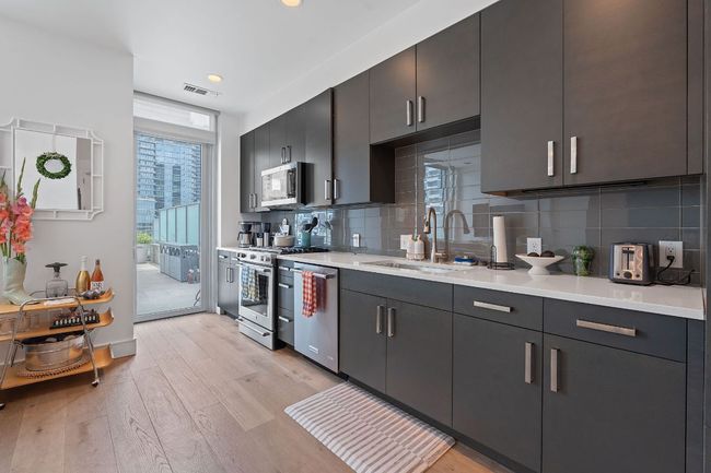 Kitchen with a sink, appliances with stainless steel finishes, light wood finished floors, light countertops, and tasteful backsplash | Image 6