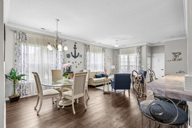 Dining space featuring wood finished floors, ornamental molding, a chandelier, a ceiling fan, and a textured ceiling | Image 7