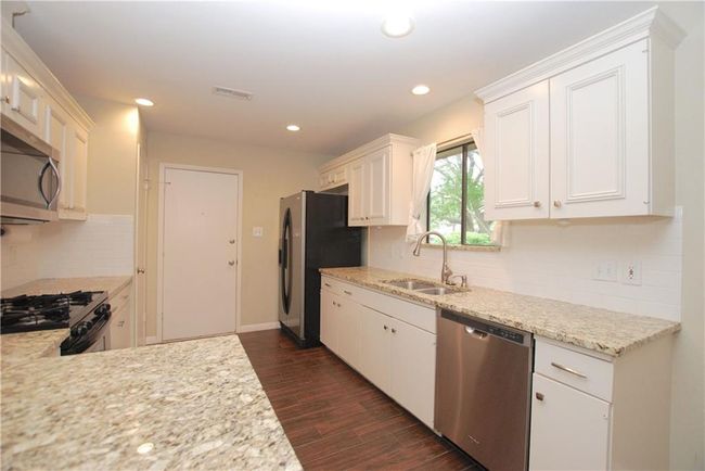 Kitchen featuring stainless steel appliances, dark wood-style flooring, white cabinets, and recessed lighting | Image 6