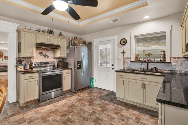 The cottage style kitchen is truly the heart of this home. Neutral colors and the granite countertops - and even the ceiling style and coloring add to the warmth of this home. Note the beautiful doorway trim that leads to the formal dining room on the left. | Image 11