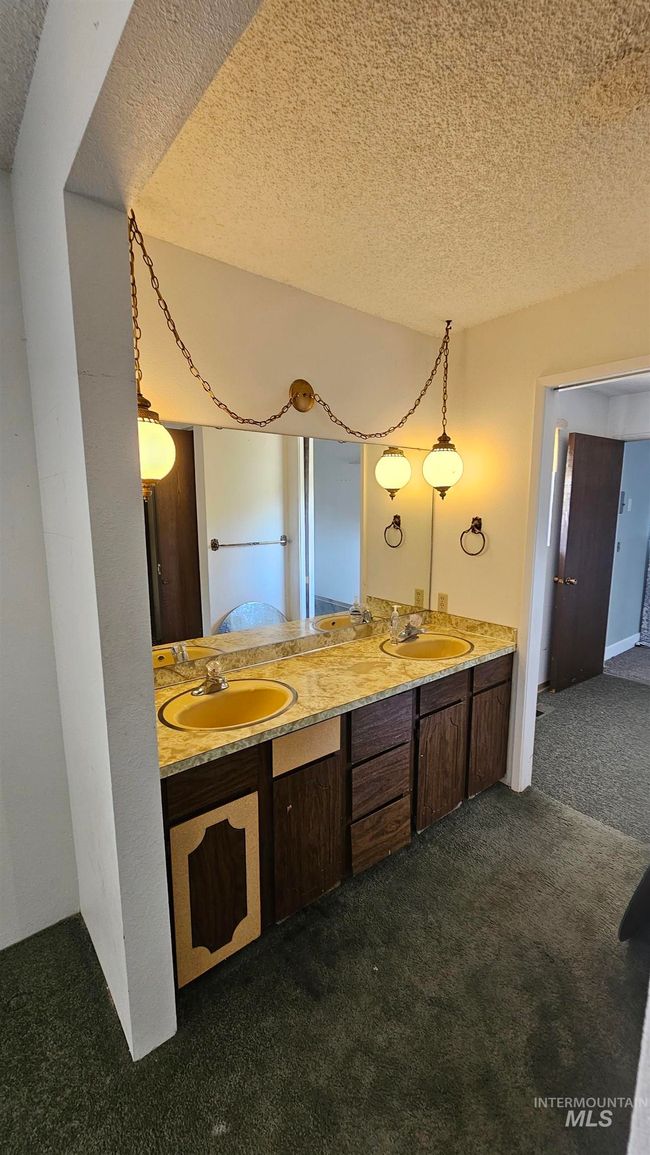 Bathroom featuring carpet floors, a textured ceiling, and double vanity | Image 14