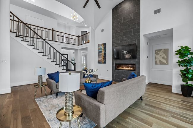 Living room with a fireplace, wood-type flooring, a notable chandelier, and high vaulted ceiling | Image 9