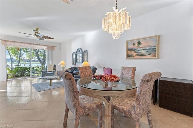 Tiled dining area with a water view and ceiling fan with notable chandelier | Image 10