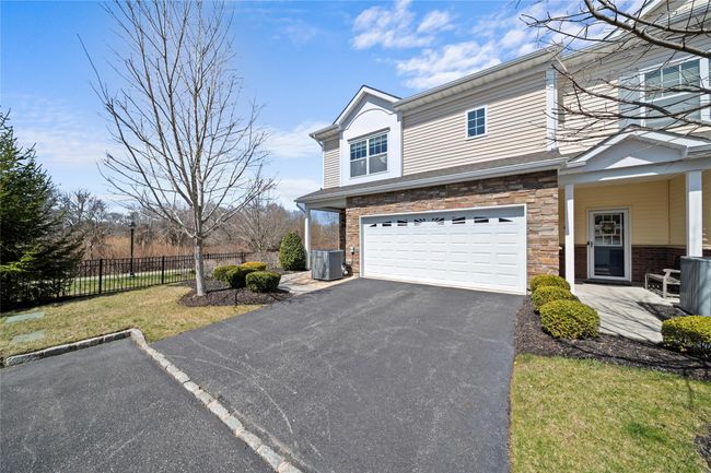 View of front of house featuring stone siding, cooling unit, an attached garage, fence, and aphalt driveway | Image 23