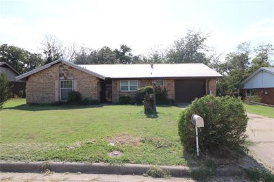 Ranch-style home with a garage and a front lawn | Image 1