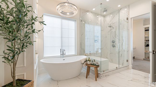 Full bath with marble finish floor, a marble finish shower, baseboards, a soaking tub, and a notable chandelier | Image 15