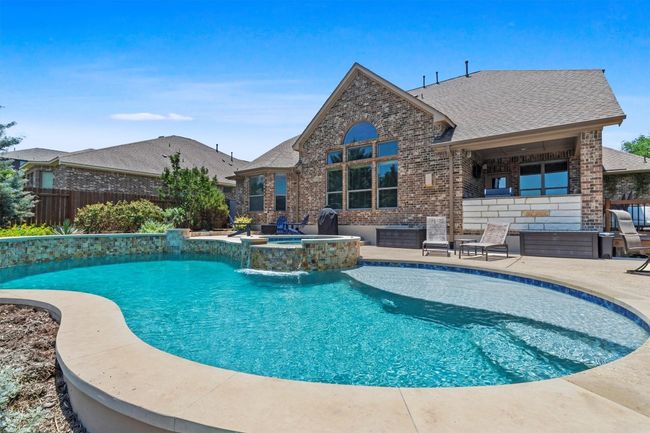 The backyard oasis you've been dreaming of—sparkling pool with a waterfall spa, lush landscaping, and room to lounge. | Image 37