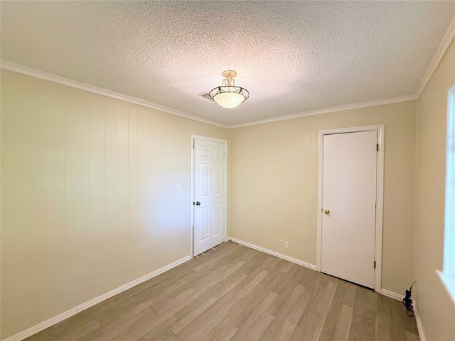 Spare room with light wood-style floors, crown molding, and a textured ceiling | Image 19