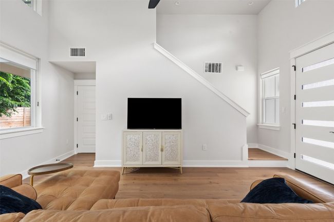 Living area featuring a towering ceiling, wood finished floors, and stairway | Image 7