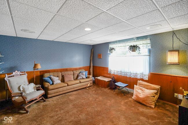 living room with wallpapered walls, wainscoting, a paneled ceiling, carpet, and wood walls | Image 26