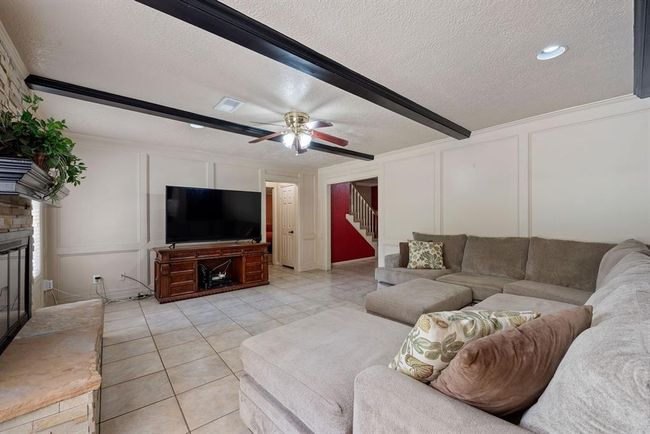 To the back off the entry, you will find a very large living area with a ceiling accented by wood beams. | Image 8
