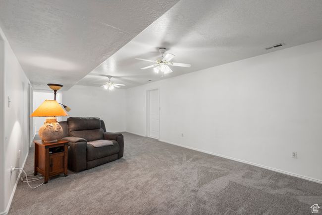 Sitting room featuring ceiling fan, carpet flooring, a textured ceiling, and baseboards | Image 23