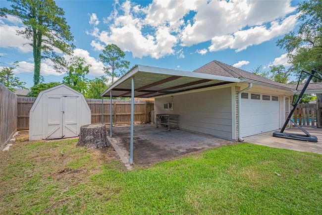Covered area off the garage is perfect for a workshop space or shaded play area. | Image 44
