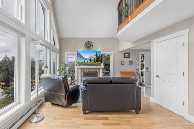 Living area featuring a baseboard radiator, a towering ceiling, plenty of natural light, and a fireplace | Image 11