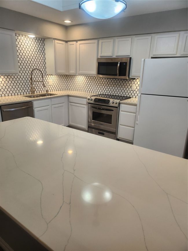 Kitchen with white cabinets, range, dishwasher, refrigerator, and a sink | Image 7