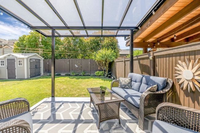 View of patio / terrace with a fenced backyard, an outdoor structure, an outdoor hangout area, and a storage unit | Image 25