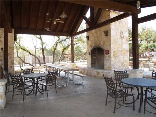 View of patio featuring an outdoor stone fireplace, outdoor dining space, a gazebo, and ceiling fan | Image 24