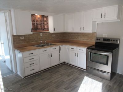 Kitchen with electric stove, white cabinetry, sink, and dark hardwood / wood-style floors | Image 3