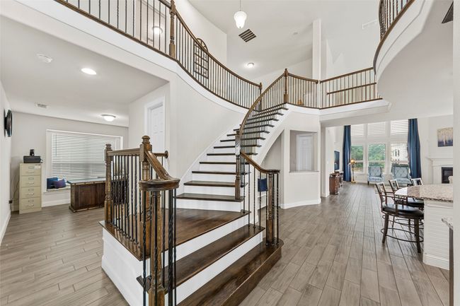 Stairs with a towering ceiling, wood finished floors, and baseboards | Image 5