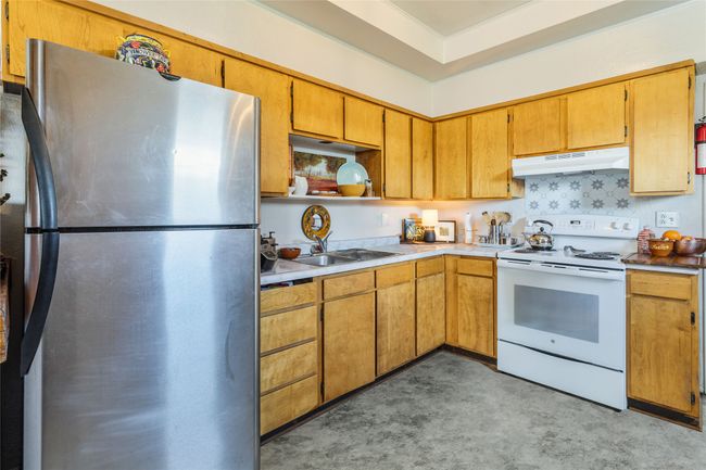 Kitchen featuring open shelves, light countertops, freestanding refrigerator, white electric stove, and under cabinet range hood | Image 13