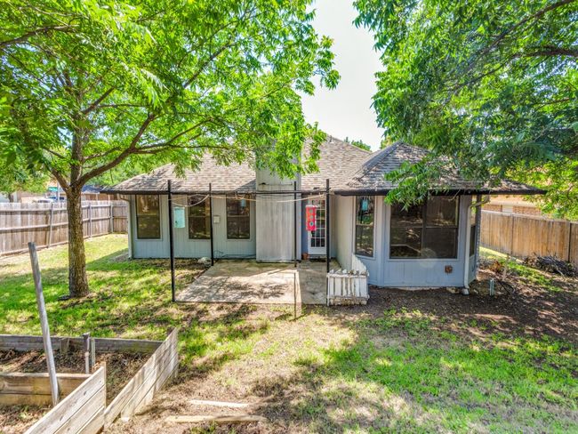 Back of house featuring a shingled roof, a patio area, a vegetable garden, and a fenced backyard | Image 5