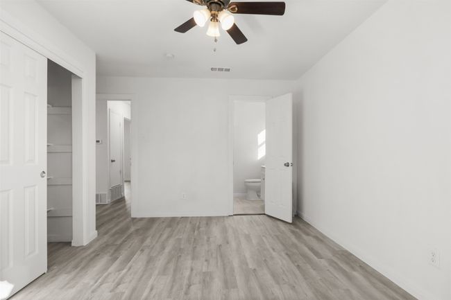 Unfurnished bedroom with ensuite bathroom, a closet, ceiling fan, and light hardwood / wood-style flooring | Image 12