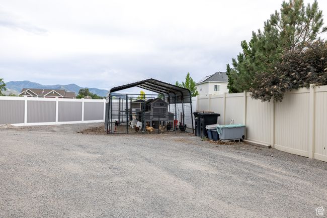 View of car parking with a fenced backyard, a mountain view, a detached carport, and exterior structure | Image 91