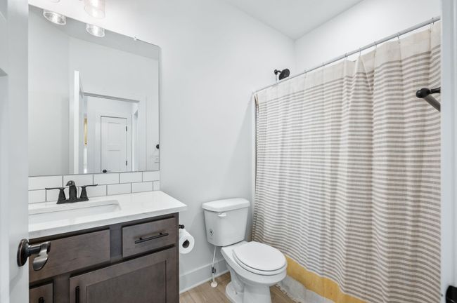 Bathroom featuring vanity, toilet, tasteful backsplash, wood finished floors, and a shower with shower curtain | Image 21