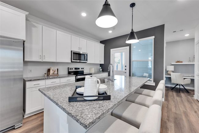 Kitchen featuring appliances with stainless steel finishes, light wood-type flooring, a sink, and white cabinetry | Image 8