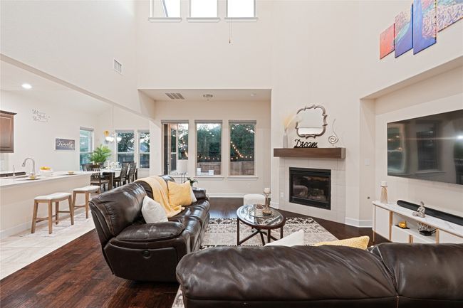 Living room featuring a high ceiling, a tiled fireplace, and dark wood-type flooring | Image 10