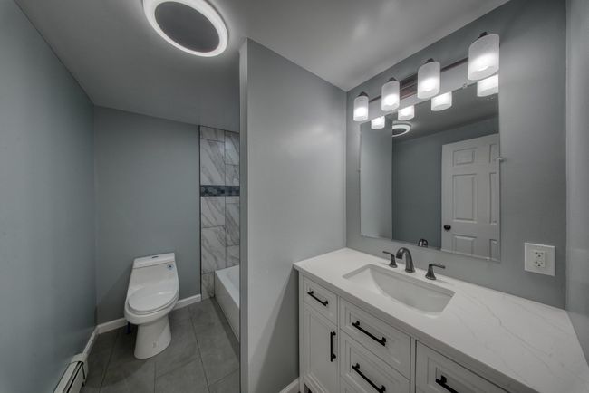 Bathroom featuring tile patterned floors, toilet, vanity, a baseboard heating unit, and baseboards | Image 22