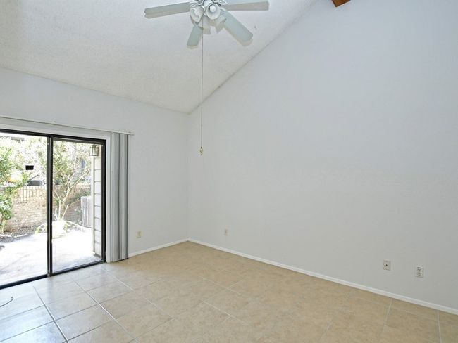 Empty room featuring light tile patterned floors, ceiling fan, vaulted ceiling, and baseboards | Image 9