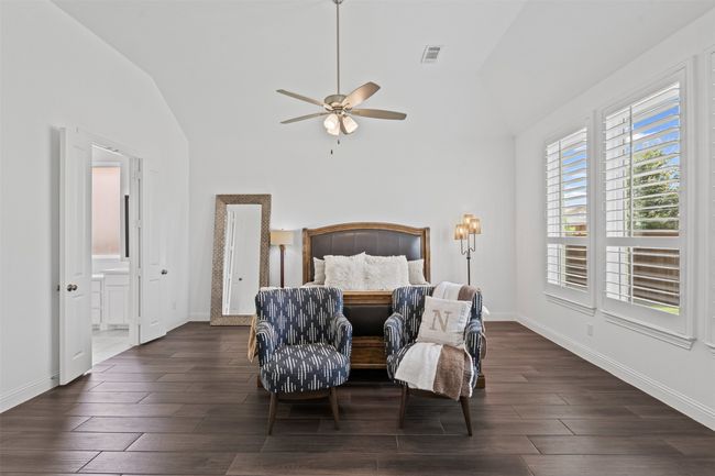 Bedroom featuring lofted ceiling, dark wood-type flooring, baseboards, ensuite bath, and ceiling fan | Image 21
