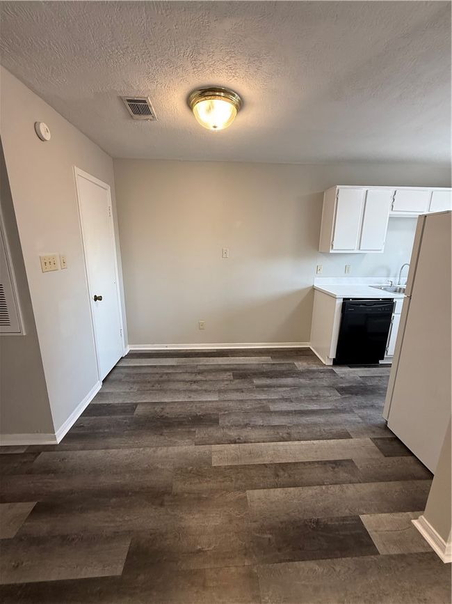 Unfurnished dining area featuring a textured ceiling and dark wood-style flooring | Image 6