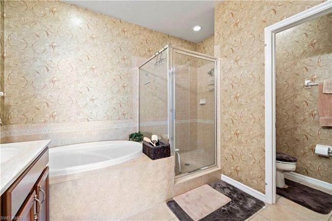 Bathroom featuring tile patterned flooring, a bath, a stall shower, and vanity | Image 21