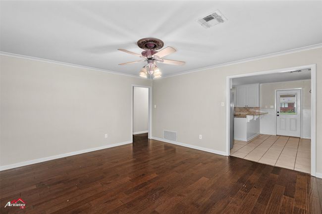 Spare room featuring a ceiling fan, crown molding, wood finished floors, and baseboards | Image 4