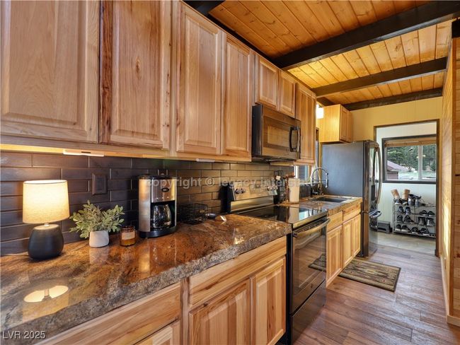 Kitchen featuring electric range, black microwave, decorative backsplash, beamed ceiling, and wood ceiling | Image 11