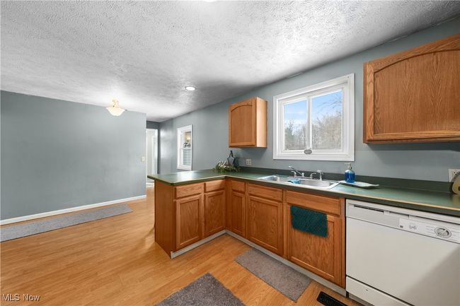 Kitchen featuring sink, a textured ceiling, light wood-type flooring, dishwasher, and kitchen peninsula | Image 11