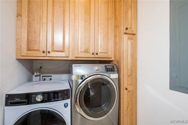 Laundry area featuring washing machine and clothes dryer, cabinet space, and electric panel | Image 34