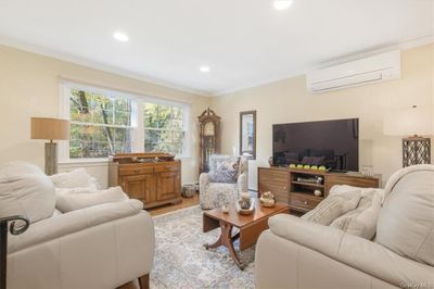 Living room with crown molding, a mounted air conditioner, hardwood floors | Image 3